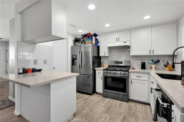 18064 Cajon St, Hesperia, CA 92345 - kitchen with stainless steel appliances, under cabinet range hood, a peninsula, a sink, and light wood-style floors