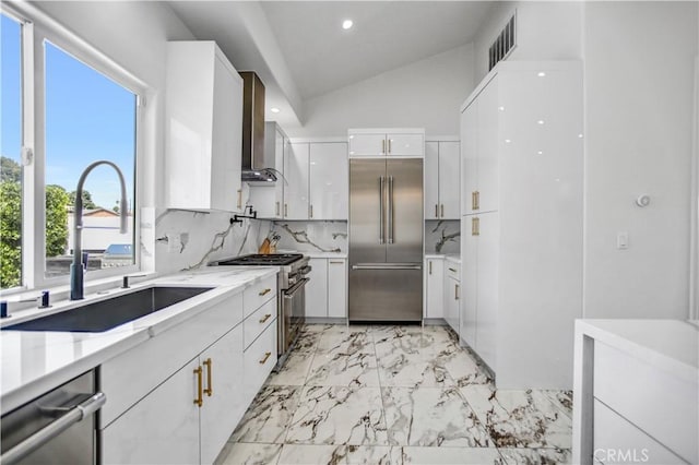 9743 Monogram Ave, Northridge, CA 91343 - kitchen featuring high quality appliances, wall chimney exhaust hood, light marble finish floors, white cabinetry, and tasteful backsplash