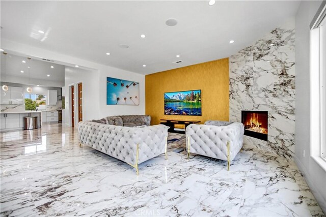 9743 Monogram Ave, Northridge, CA 91343 - living room with marble tiled floors, recessed lighting, a high end fireplace, an accent wall, and stone wall
