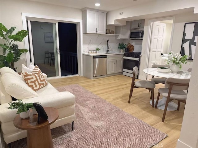 2838 Lambert Dr, Los Angeles, CA 90068 - kitchen with stainless steel appliances, light countertops, light wood finished floors, a sink, and tasteful backsplash