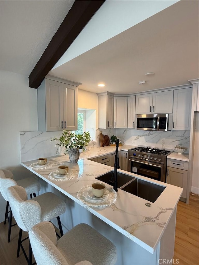 2838 Lambert Dr, Los Angeles, CA 90068 - kitchen with appliances with stainless steel finishes, tasteful backsplash, a sink, light stone counters, and a peninsula
