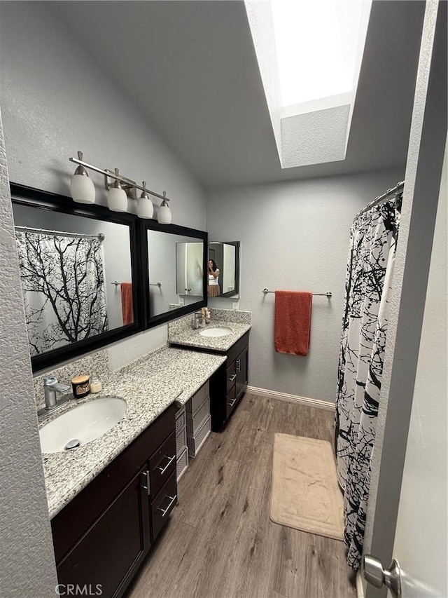 2651 Annapolis Cir, San Bernardino, CA 92408 - full bathroom with wood finished floors, a skylight, double vanity, baseboards, and lofted ceiling