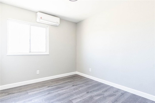 2008 Sequoia Dr, Barstow, CA 92311 - spare room featuring an AC wall unit, wood finished floors, and baseboards