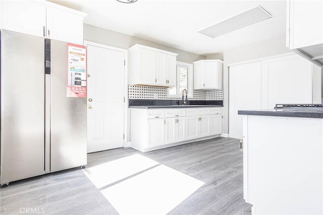 2008 Sequoia Dr, Barstow, CA 92311 - kitchen featuring freestanding refrigerator, dark countertops, white cabinetry, light wood-type flooring, and backsplash