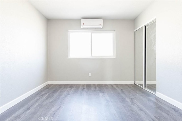 2008 Sequoia Dr, Barstow, CA 92311 - unfurnished bedroom featuring a wall mounted AC, wood finished floors, baseboards, and a closet