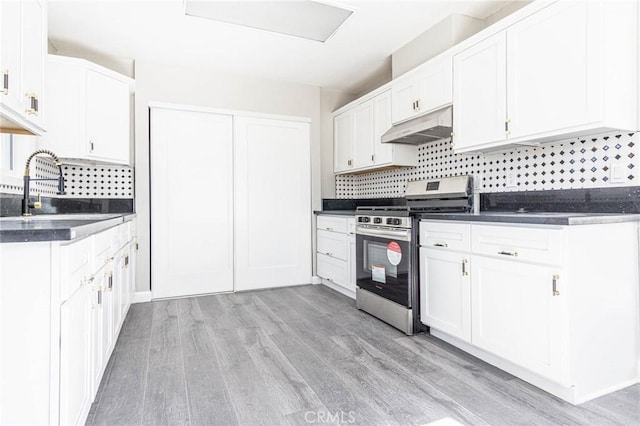 2008 Sequoia Dr, Barstow, CA 92311 - kitchen featuring gas range, under cabinet range hood, dark countertops, a sink, and tasteful backsplash