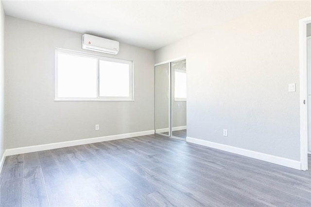 2008 Sequoia Dr, Barstow, CA 92311 - unfurnished bedroom with a wall mounted AC, wood finished floors, baseboards, and a closet