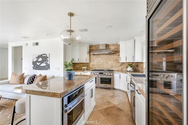 245 Palmer St, Costa Mesa, CA 92627 - kitchen with wall chimney exhaust hood, appliances with stainless steel finishes, decorative backsplash, and light stone counters