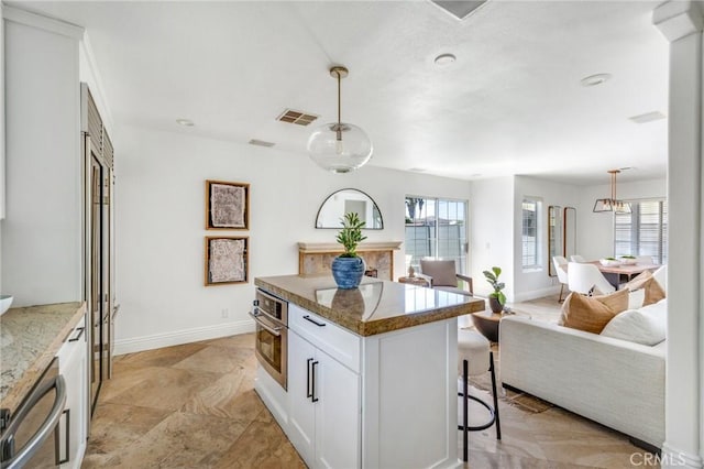 245 Palmer St, Costa Mesa, CA 92627 - kitchen with oven, open floor plan, baseboards, white cabinets, and a breakfast bar