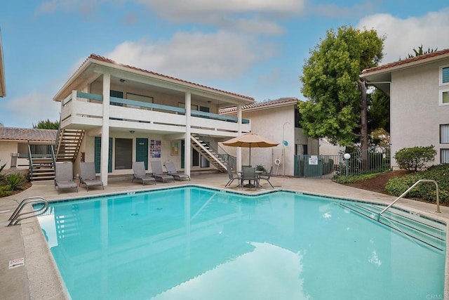 2308 Altisma Way Unit 123, Carlsbad, CA 92009 - rear view of house with stairway, a community pool, a tiled roof, and a patio