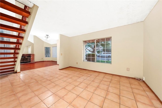 37538 Stonegate Ln, Palmdale, CA 93552 - empty room with vaulted ceiling, a fireplace, light tile patterned flooring, and baseboards