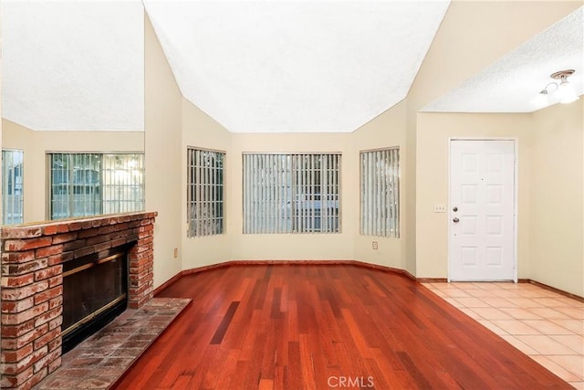 37538 Stonegate Ln, Palmdale, CA 93552 - unfurnished living room with lofted ceiling, a fireplace, wood finished floors, baseboards, and a textured ceiling