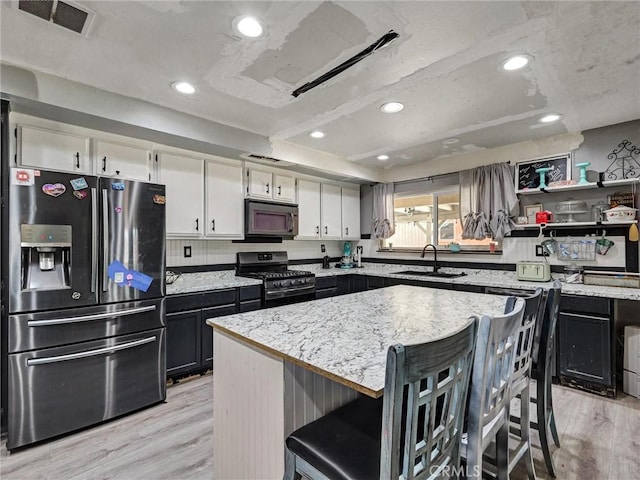 20715 Teton Rd, Apple Valley, CA 92308 - kitchen with appliances with stainless steel finishes, light wood-style flooring, a kitchen bar, a center island, and white cabinetry