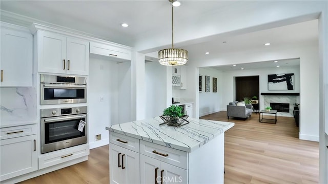 53 Via Armilla, San Clemente, CA 92673 - kitchen with white cabinetry, light stone countertops, light wood-type flooring, hanging light fixtures, and a center island