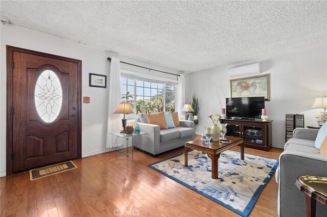 143581/2 Jeanette Ln, Baldwin Park, CA 91706 - living room with a wall mounted air conditioner, a textured ceiling, hardwood / wood-style floors, and baseboards