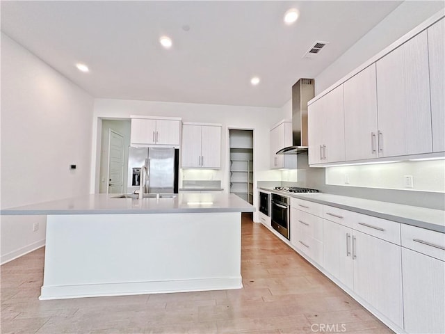229 Radial, Irvine, CA 92618 - kitchen with appliances with stainless steel finishes, wall chimney range hood, a center island with sink, light countertops, and recessed lighting