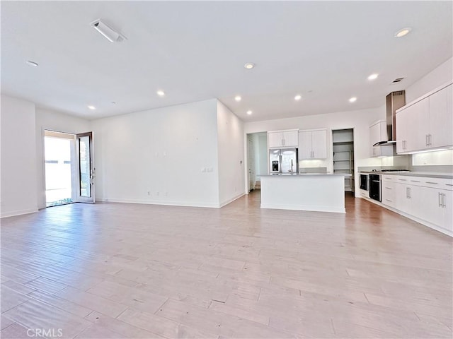229 Radial, Irvine, CA 92618 - kitchen with wall chimney range hood, open floor plan, stainless steel refrigerator with ice dispenser, recessed lighting, and white cabinetry