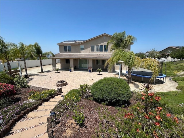 17426 Fairbreeze Ct, Riverside, CA 92504 - rear view of house with a fire pit, a trampoline, a patio, solar panels, and a fenced backyard