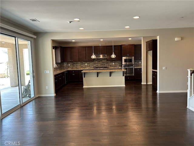 17426 Fairbreeze Ct, Riverside, CA 92504 - kitchen featuring appliances with stainless steel finishes, under cabinet range hood, backsplash, dark wood finished floors, and recessed lighting