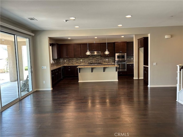 17426 Fairbreeze Ct, Riverside, CA 92504 - kitchen featuring appliances with stainless steel finishes, under cabinet range hood, tasteful backsplash, dark wood-type flooring, and recessed lighting