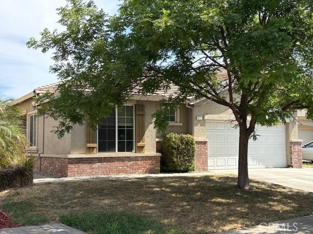 619 Coppola Ct, Merced, CA 95348 - obstructed view of property with stucco siding, driveway, a garage, and brick siding