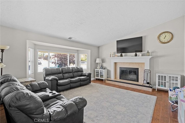 4198 Woodland St, Santa Maria, CA 93455 - living area with a textured ceiling, wood finished floors, vaulted ceiling, and a tiled fireplace