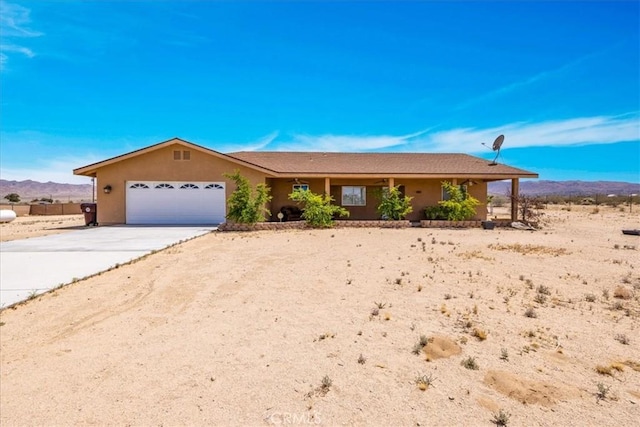 63357 Uranium Rd, Joshua Tree, CA 92252 - ranch-style house featuring a garage, driveway, a mountain view, and stucco siding
