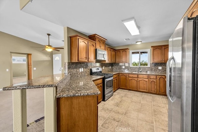 63357 Uranium Rd, Joshua Tree, CA 92252 - kitchen featuring appliances with stainless steel finishes, brown cabinets, a peninsula, decorative backsplash, and a sink