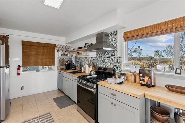 55436 Cone Blvd, Landers, CA 92285 - kitchen with stainless steel appliances, wall chimney exhaust hood, butcher block countertops, open shelves, and decorative backsplash