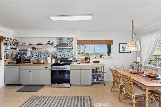 55436 Cone Blvd, Landers, CA 92285 - kitchen with wall chimney range hood, stainless steel appliances, decorative backsplash, light tile patterned floors, and light countertops