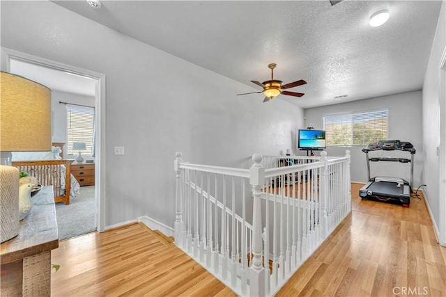 2832 Owens Way, Rosamond, CA 93560 - hallway featuring an upstairs landing, wood finished floors, a textured ceiling, and baseboards