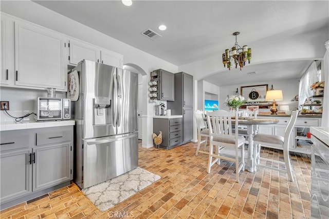 2832 Owens Way, Rosamond, CA 93560 - kitchen featuring stainless steel fridge with ice dispenser, gray cabinets, a chandelier, arched walkways, and brick patterned flooring