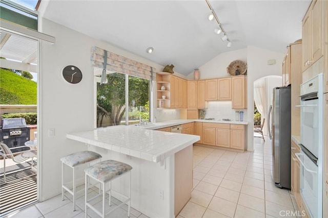 48 Siena, Laguna Niguel, CA 92677 - kitchen with light brown cabinetry, a peninsula, vaulted ceiling, freestanding refrigerator, and light tile patterned floors