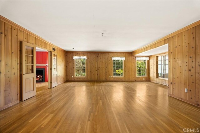 85 S San Rafael Ave, Pasadena, CA 91105 - unfurnished living room with wooden walls, light wood finished floors, a warm lit fireplace, baseboards, and ornamental molding