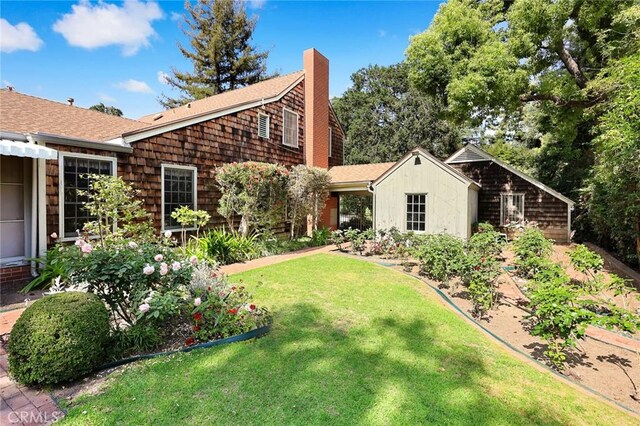 85 S San Rafael Ave, Pasadena, CA 91105 - view of side of property with a chimney, a lawn, a shingled roof, and a vegetable garden