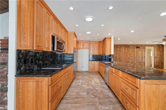 1825 Leola St, Lomita, CA 90717 - kitchen featuring appliances with stainless steel finishes, a peninsula, backsplash, ceiling fan, and dark stone countertops