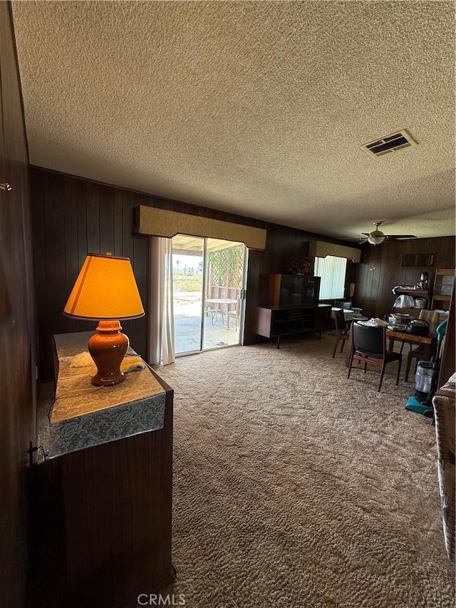 72400 El Paseo Dr Unit 29, Palms, CA 92277 - living area featuring a textured ceiling, wood walls, carpet floors, and a ceiling fan