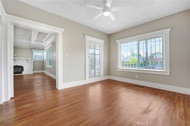 142 S Ardmore Ave, Los Angeles, CA 90004 - spare room featuring wood finished floors, a stone fireplace, baseboards, a textured ceiling, and a ceiling fan