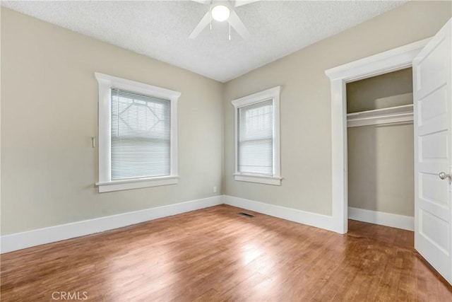 142 S Ardmore Ave, Los Angeles, CA 90004 - unfurnished bedroom featuring multiple windows, wood finished floors, a closet, a textured ceiling, and baseboards