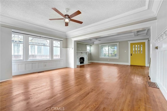 142 S Ardmore Ave, Los Angeles, CA 90004 - unfurnished living room with a textured ceiling, a ceiling fan, a fireplace with flush hearth, light wood-style floors, and a decorative wall