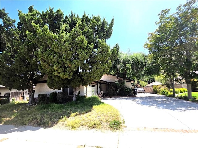 2108 Ardenwood Ave, Simi Valley, CA 93063 - view of property hidden behind natural elements with stucco siding, a garage, and driveway