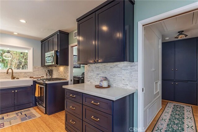 16733 Archwood St, Van Nuys, CA 91406 - kitchen featuring appliances with stainless steel finishes, a sink, light wood-style floors, decorative backsplash, and light countertops