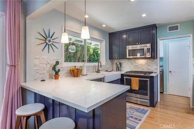 16733 Archwood St, Van Nuys, CA 91406 - kitchen with stainless steel appliances, a peninsula, backsplash, a sink, and light wood-style floors