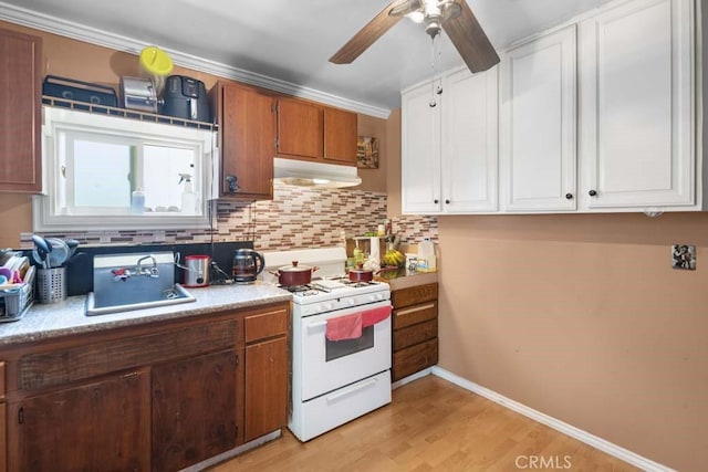 11073 Andrews St, South El Monte, CA 91733 - kitchen featuring white gas stove, under cabinet range hood, a ceiling fan, decorative backsplash, and light wood-type flooring
