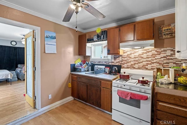 11073 Andrews St, South El Monte, CA 91733 - kitchen featuring white gas stove, under cabinet range hood, ornamental molding, backsplash, and ceiling fan