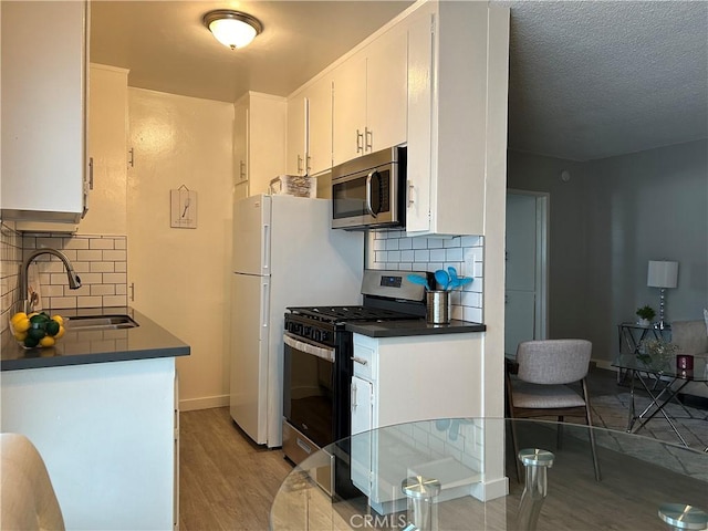 3337 S Durango Ave, Los Angeles, CA 90034 - kitchen featuring stainless steel appliances, a sink, dark countertops, decorative backsplash, and a textured ceiling