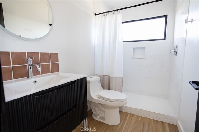 3977 Sage Ave, Yucca Valley, CA 92284 - full bathroom featuring wood finished floors, tiled shower, vanity, and backsplash