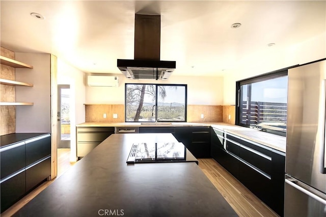 3977 Sage Ave, Yucca Valley, CA 92284 - kitchen with wall chimney range hood, modern cabinets, stainless steel fridge, dark cabinetry, and a sink