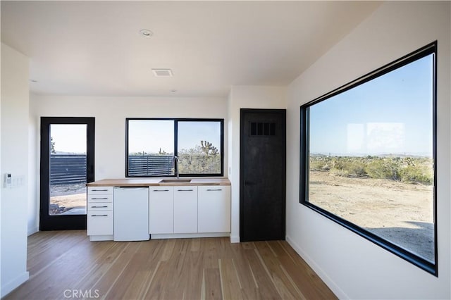 3977 Sage Ave, Yucca Valley, CA 92284 - kitchen with white cabinetry, white dishwasher, and light wood-style flooring