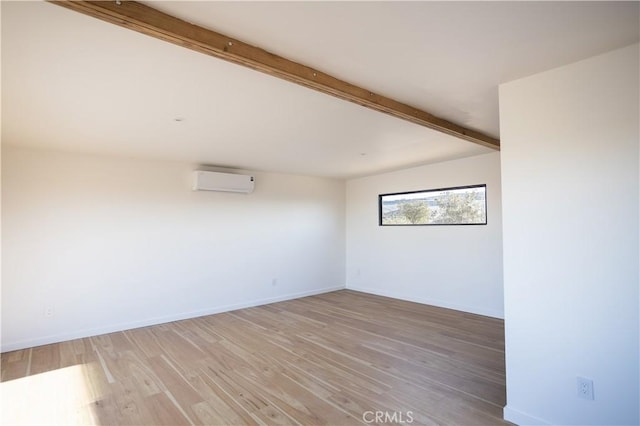 3977 Sage Ave, Yucca Valley, CA 92284 - unfurnished room with a wall mounted AC, beamed ceiling, and light wood-style flooring